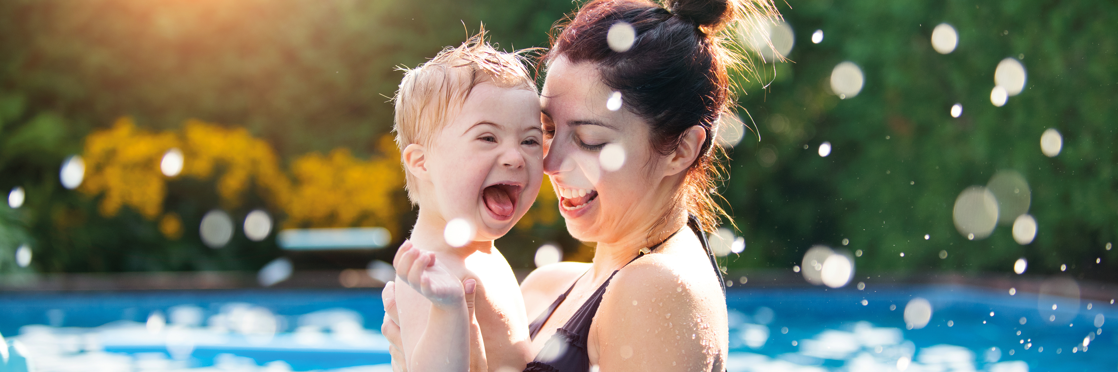 Vrouw en kind met syndroom van Down genieten in het zwembad.