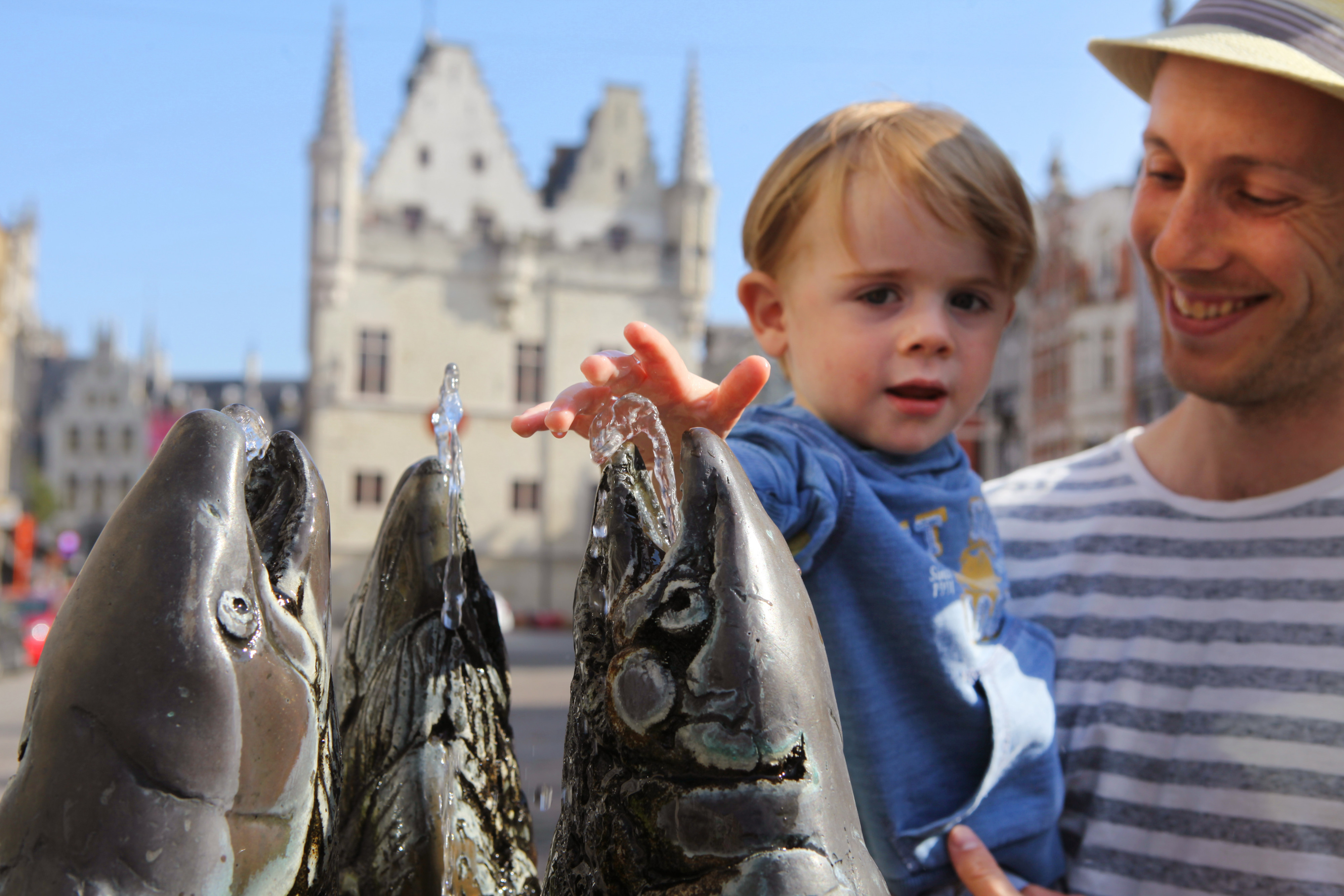 man en kindje aan standbeeld met vissen