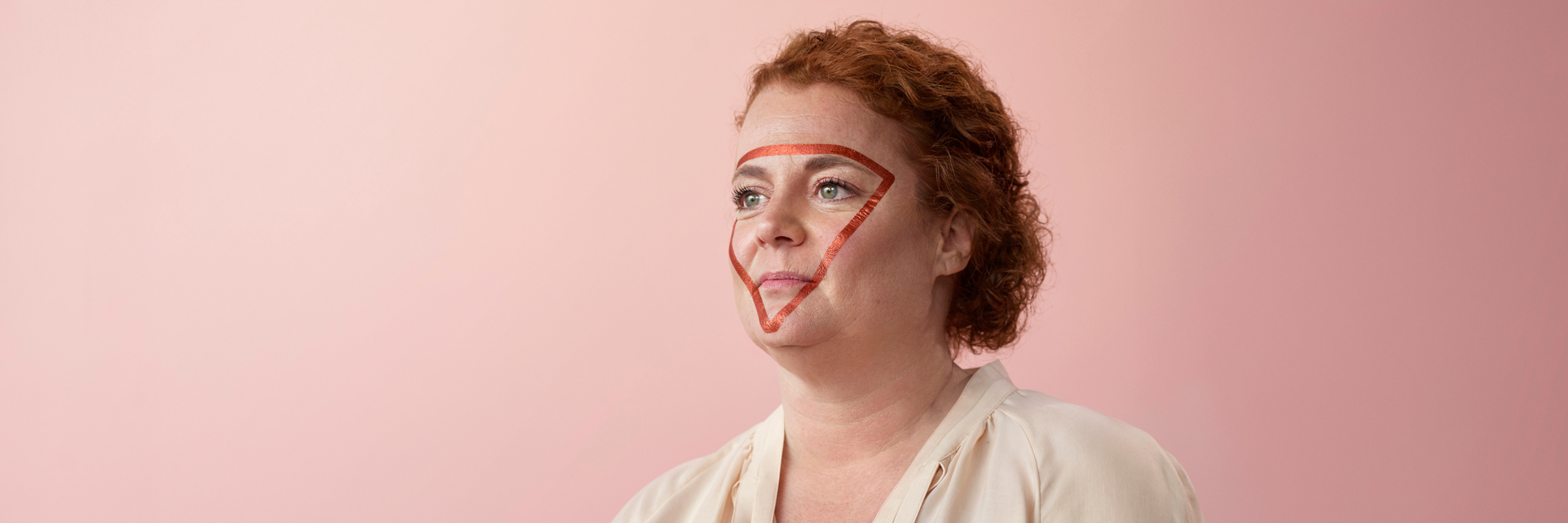 Een poserende vrouw met rode versiering in driehoeksvorm op het gezicht