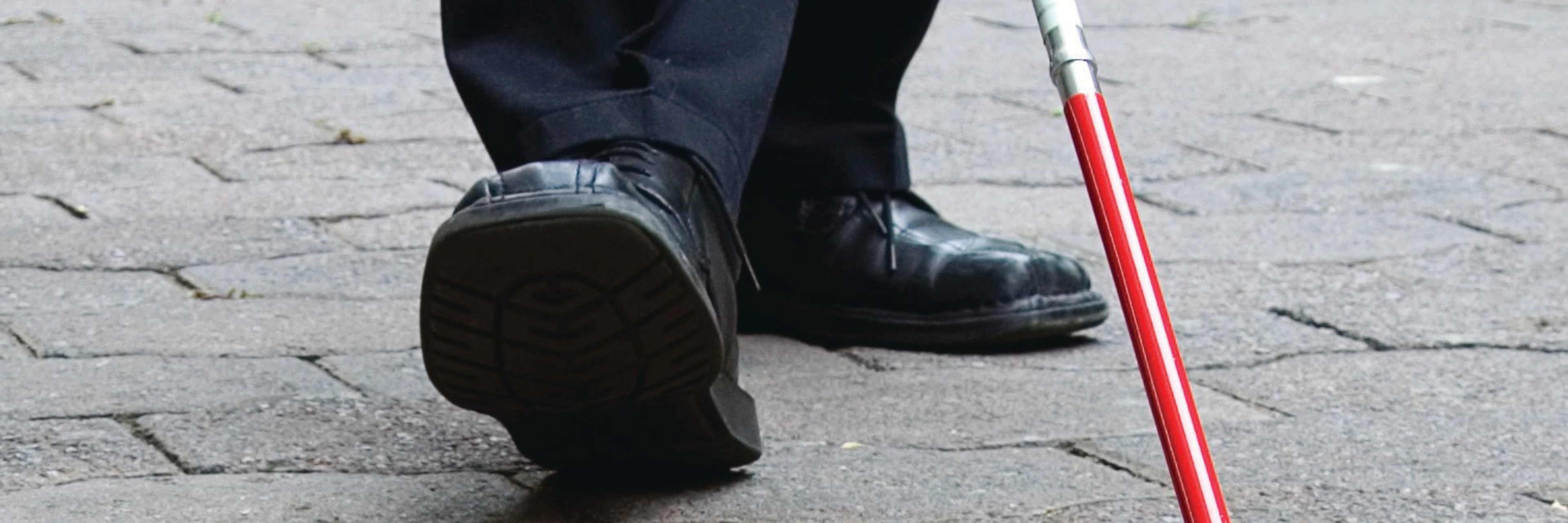 Close-up van schoenen van een man met een wandelstok voor blinden