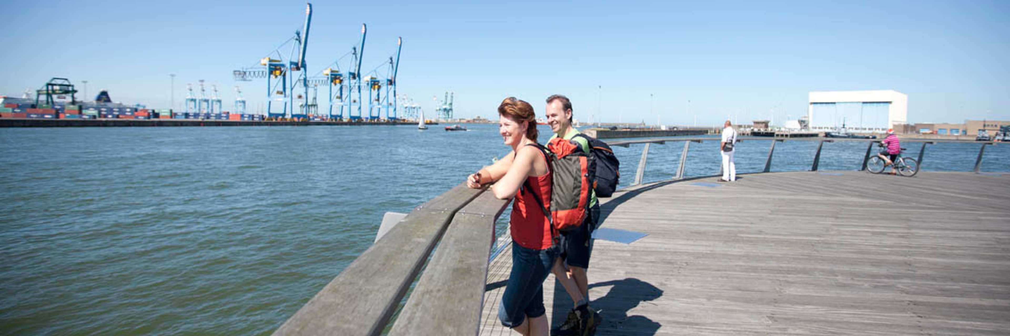 Man en vrouw kijken vanop de dijk naar het uitzicht van de zee in Zeebrugge