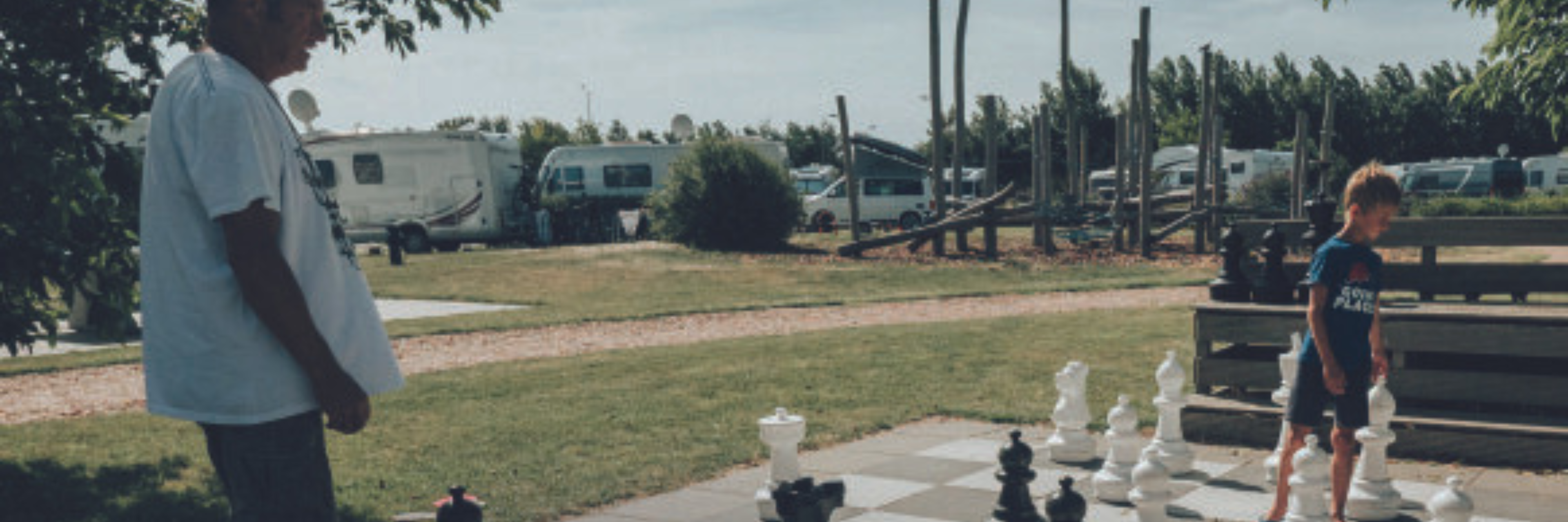 Een jongen en een man spelen met schaakstukken op een camping
