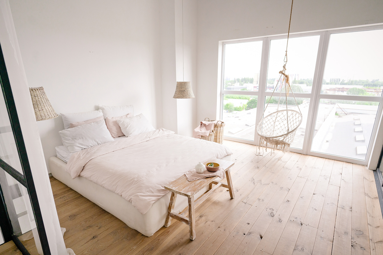 Een strakke slaapkamer in neutral stijl met een lichte parketvloer en witte muren