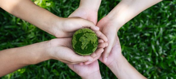 Verschillende paar handen die een groene aardbol vasthouden.