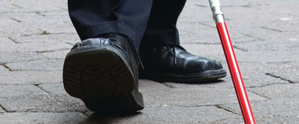 Close-up van schoenen van een man met een wandelstok voor blinden