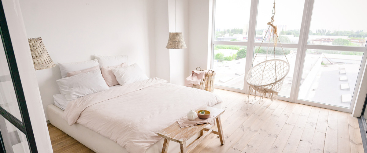 Een strakke slaapkamer in neutral stijl met een lichte parketvloer en witte muren